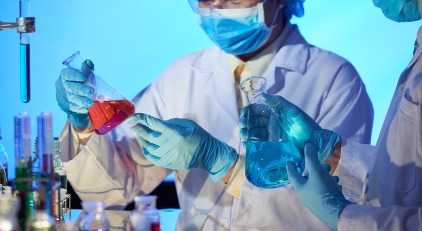Dois químicos em um laboratório analisando líquidos em recipientes.