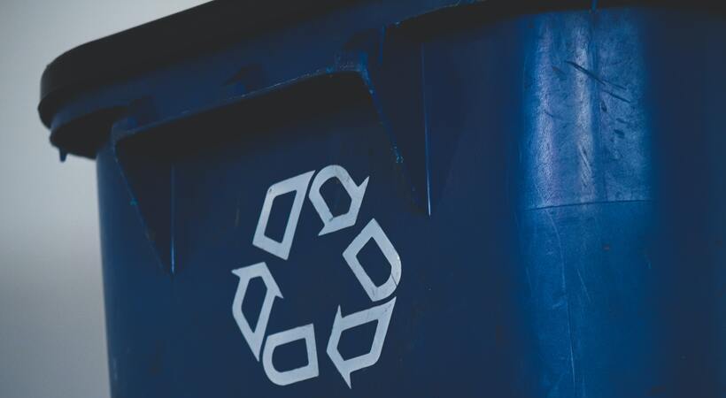 Lixeira azul escura com símbolo de reciclagem. 