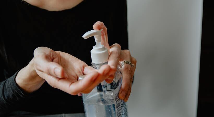 Mulher usando álcool gel nas mãos. 