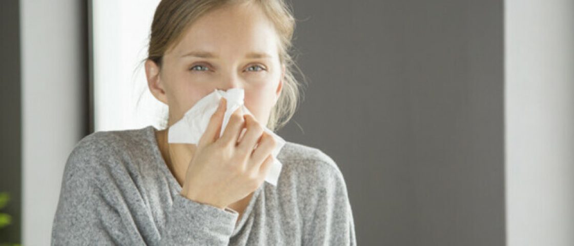 Pensive unhappy girl suffering from running nose. Young woman covering nose with tissue. Snuffle concept